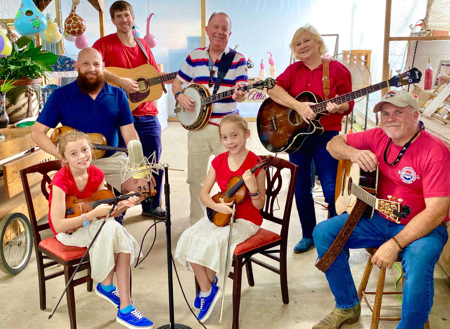 Fiddlin Fluds posed on porch positioned to play the fiddles